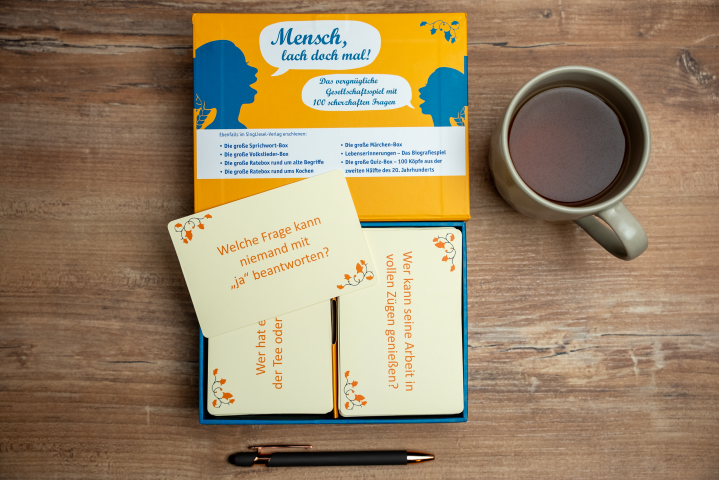 Geöffnete Ratebox „Lach doch mal“ vom SingLiesel Verlag mit Quiz-Karten rund um die lustigsten Scherzfragen – Aktivierungsspiel für Senioren.