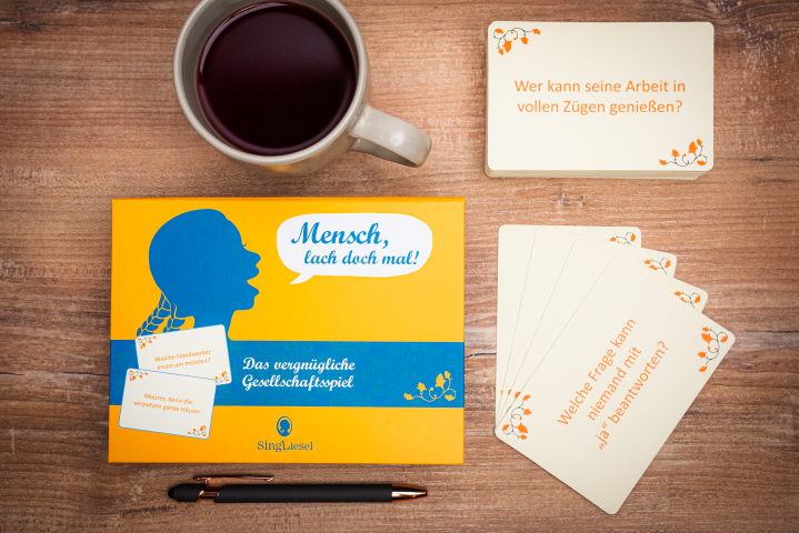 Vorderseite der Ratebox „Lach doch mal“ vom Singliesel Verlag – Ein Quiz-Spiel rund die lustigsten Scherzfragen – ein ideales Aktivierungsspiel für Senioren. Daneben sind einige Spielkarten zu sehen.